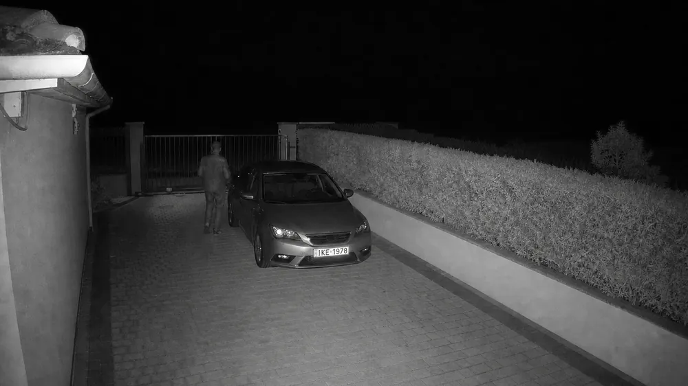 Σκηνή επίδειξης, νυχτερινή λήψη με υπέρυθρο: αυτοκίνητο μπροστά στην αυλόπορτα και κάποιος που περπατά δίπλα του
